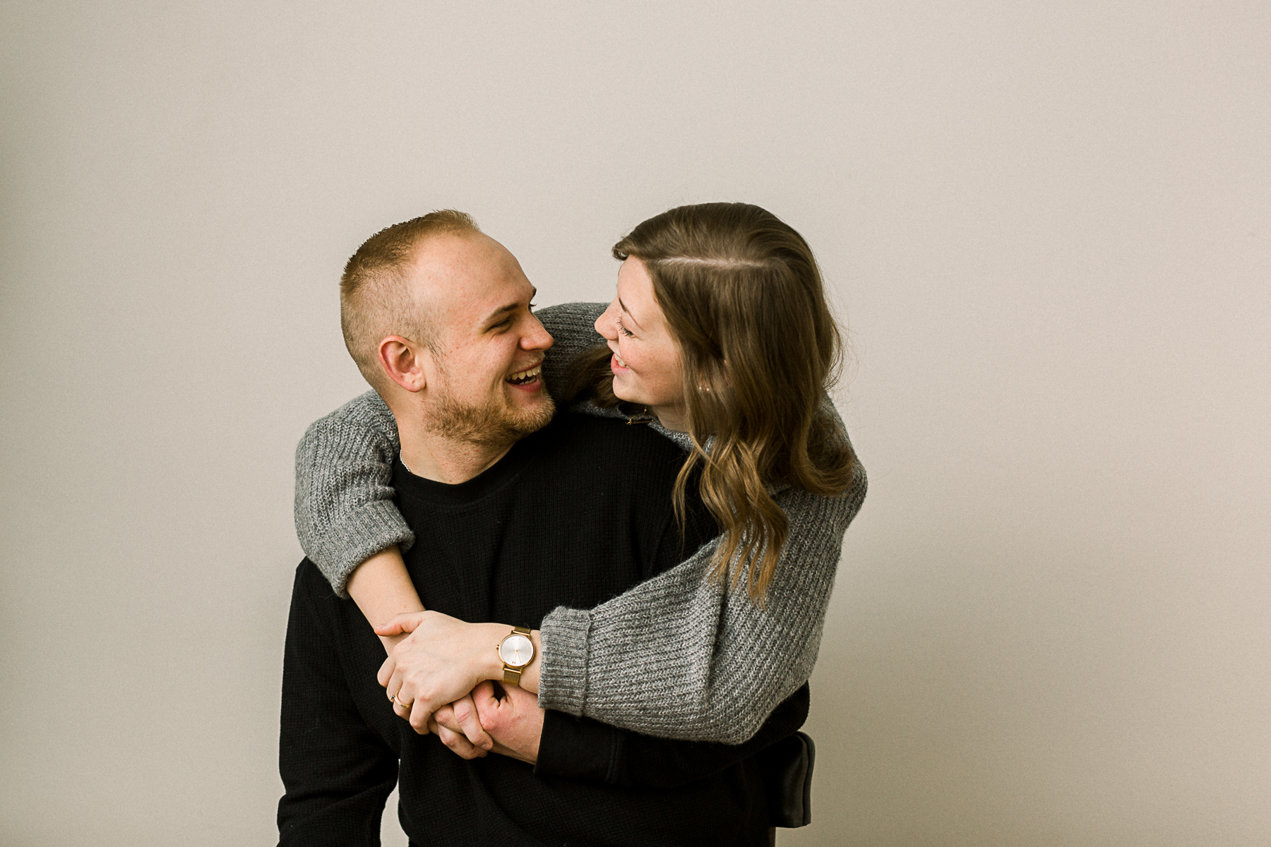 couple laughing together and embracing in a bright white studio space